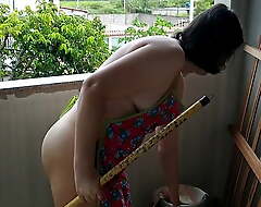 Nudist housewife cleaning balcony